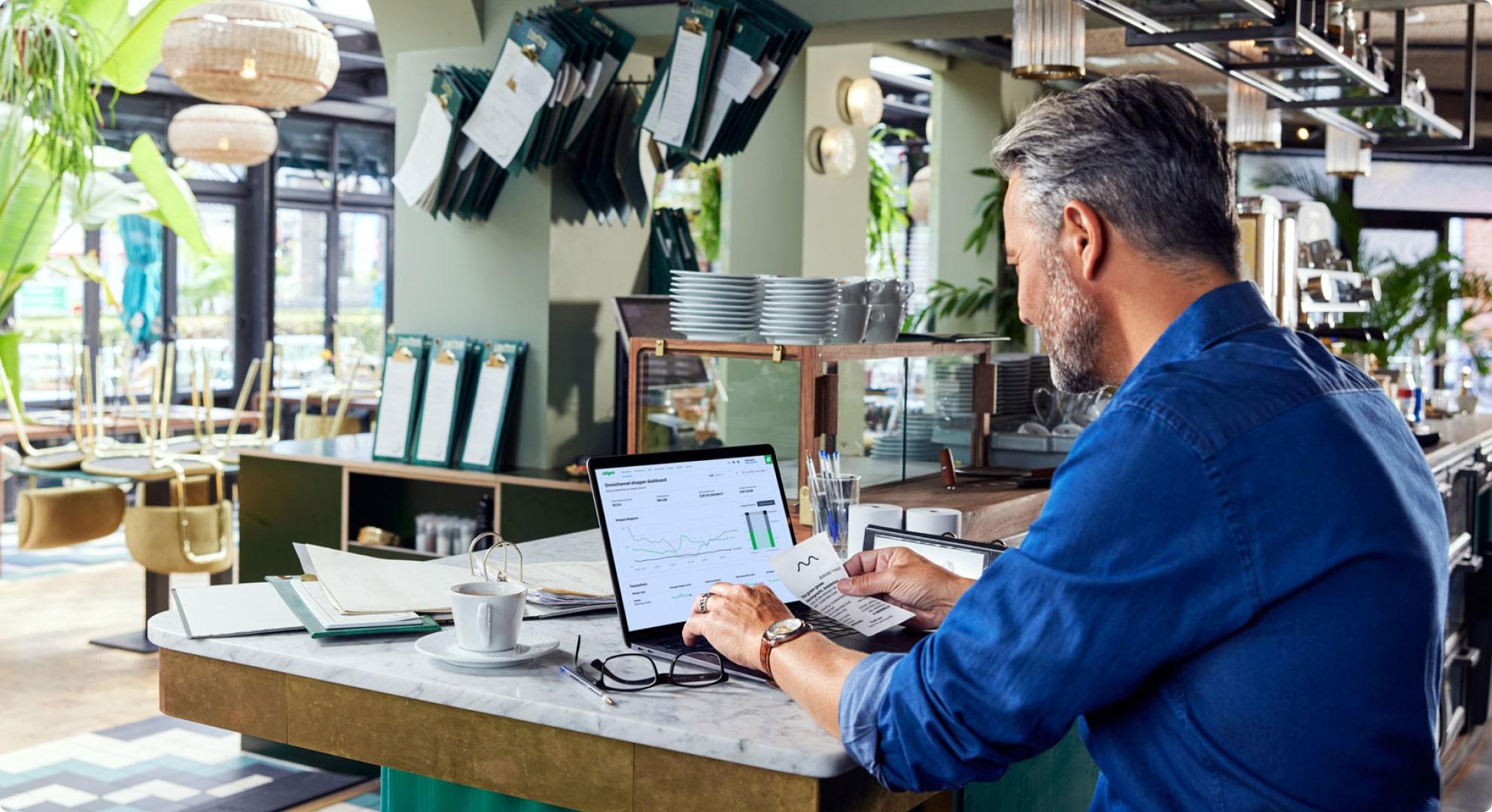 Restaurant manager sitting in an empty restaurant on a laptop