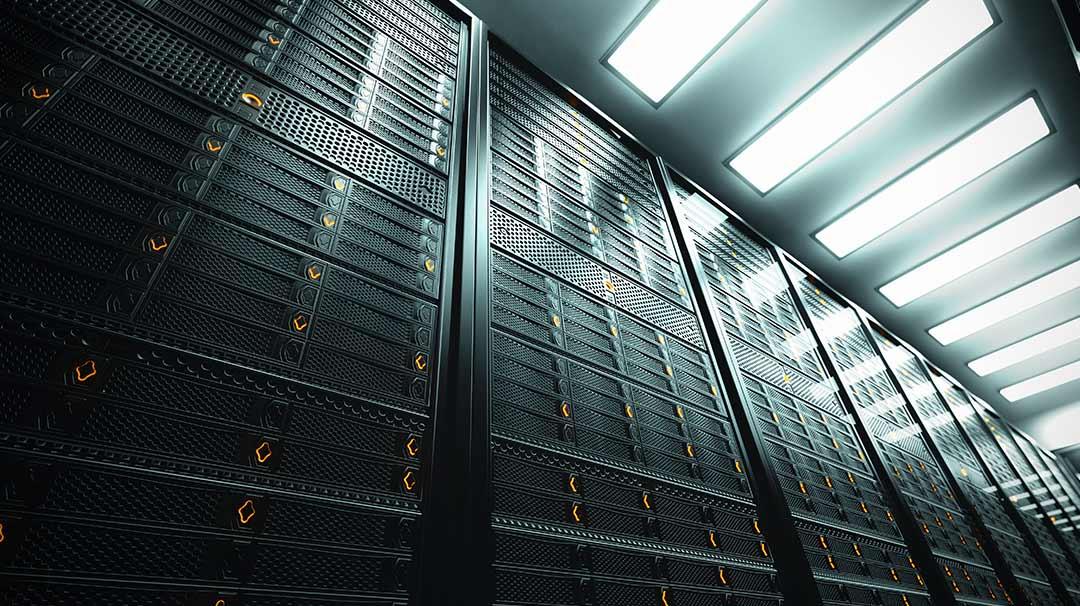 Interior de centro de datos con hileras de bastidores de servidores bajo luces de techo brillantes.