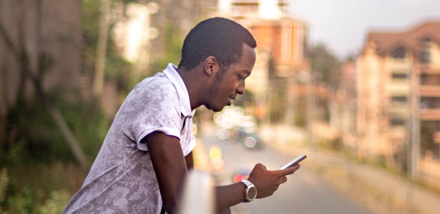 Man standing by the road focused on his smartphone.