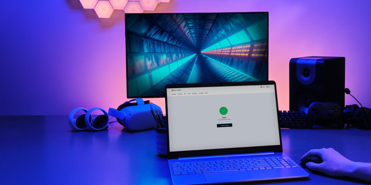 Bärbar dator på skrivbord med Adyen-utcheckningsskärm, speltillbehör och RGB-belysning runt omkring.