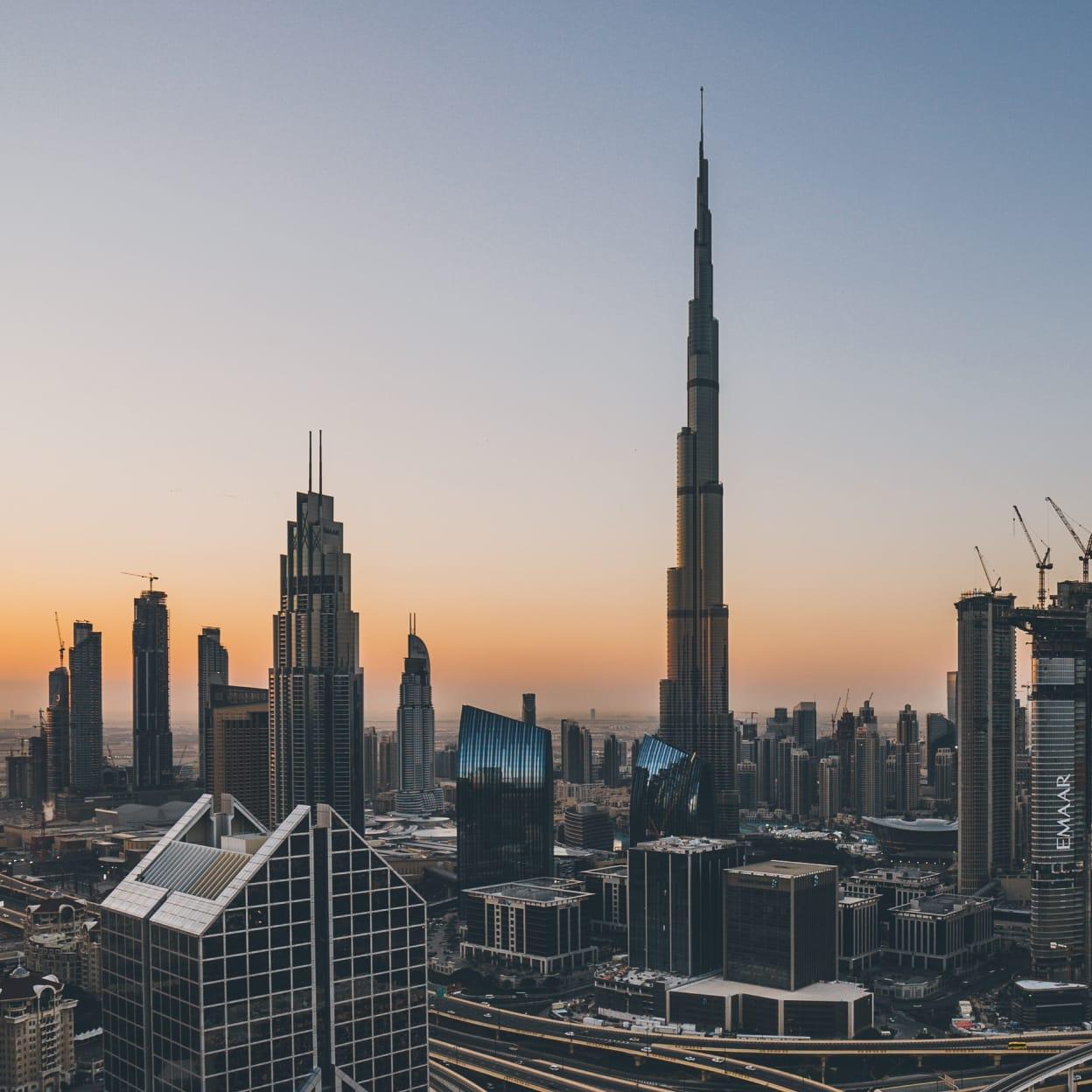 Sunset over a bustling cityscape with skyscrapers and the tallest building piercing the sky.