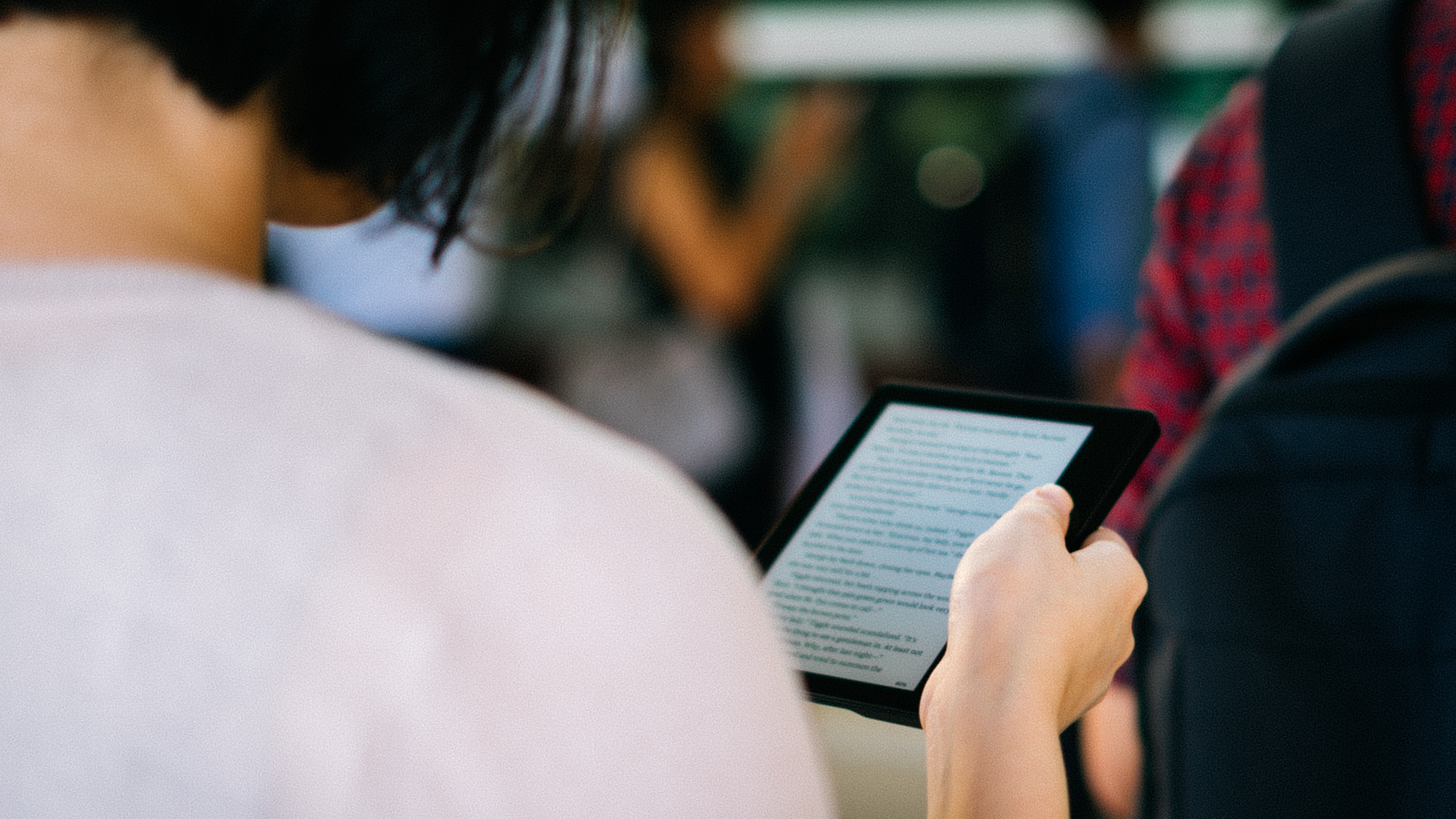 Osoba czytająca tekst na ekranie tabletu w zatłoczonym obszarze