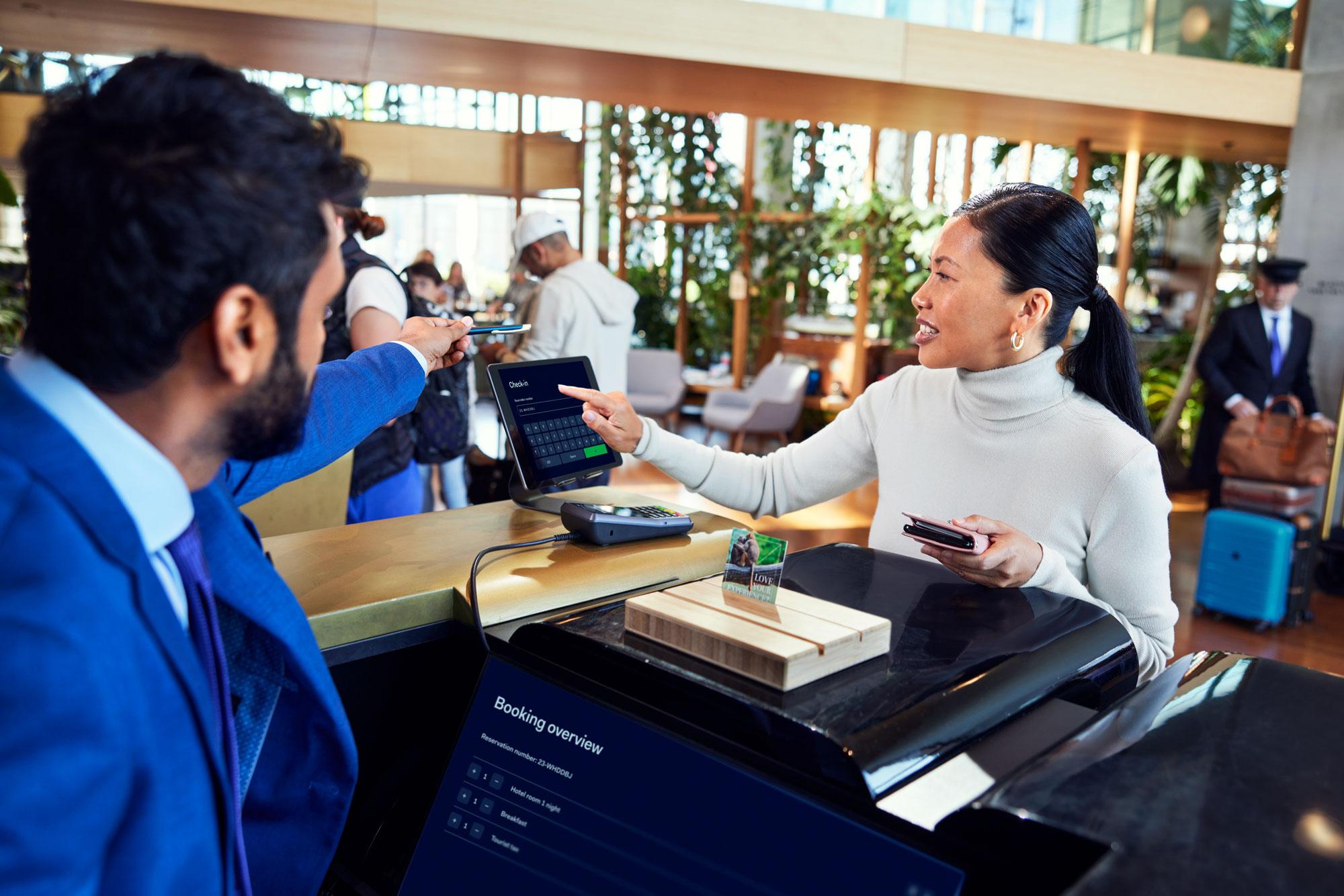 A woman checking into a hotel by filling her detail on a table at a reception desk.