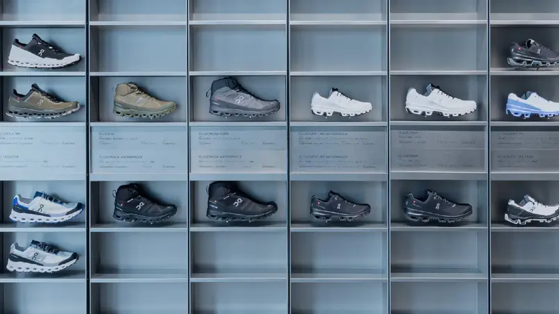 A variety of sports shoes on display shelves neatly arranged in rows and columns.