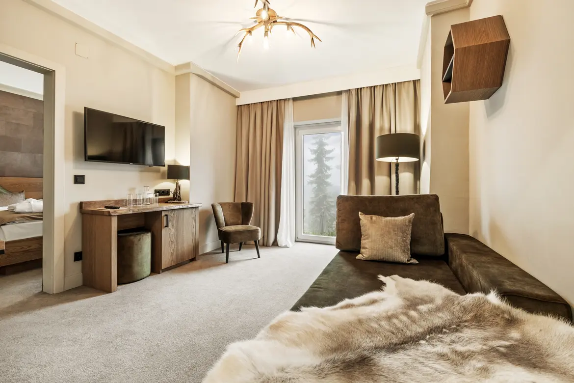 Ein elegantes Hotelzimmer mit gemütlichem Sitzbereich und Blick auf den Balkon bei Aldiana