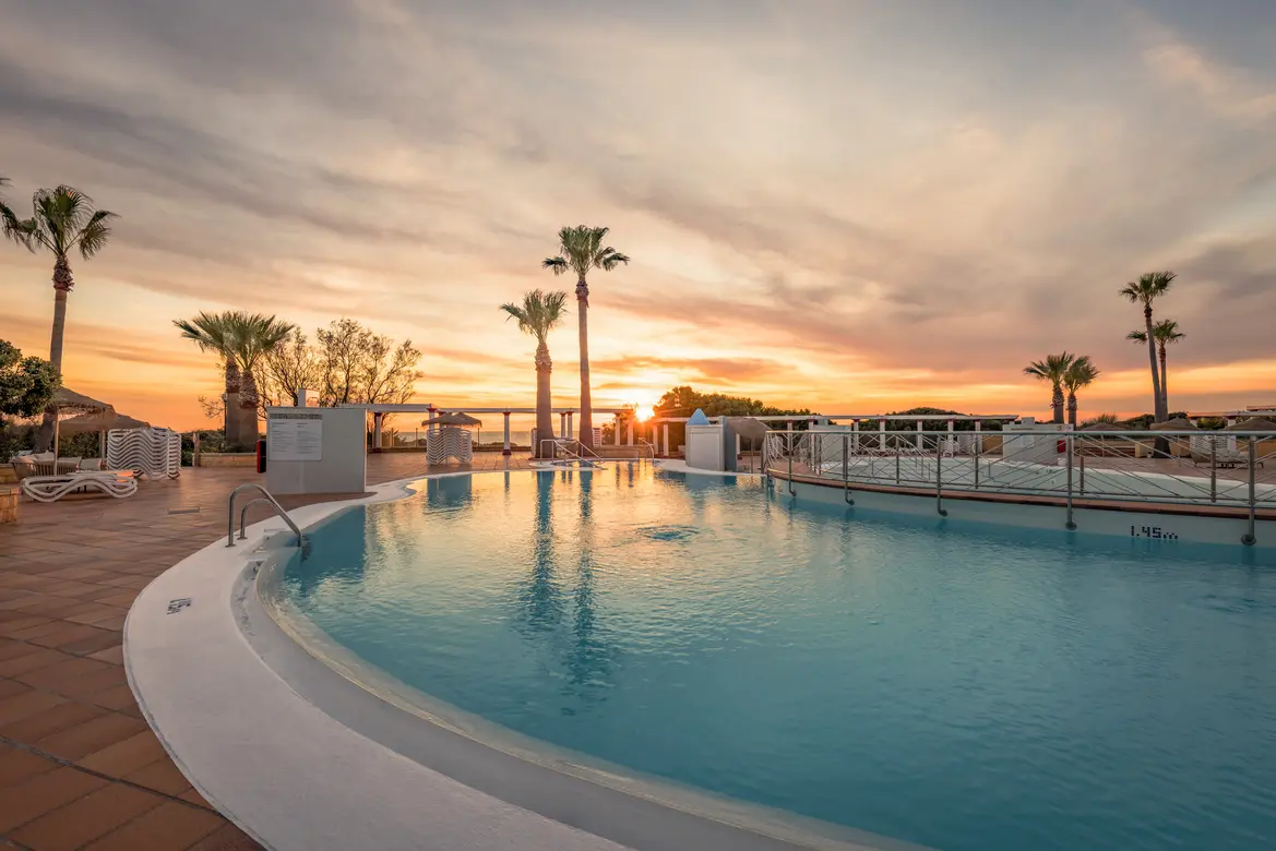 Pool Terrasse beim Sonnenuntergang mit Pool und Palmen 
