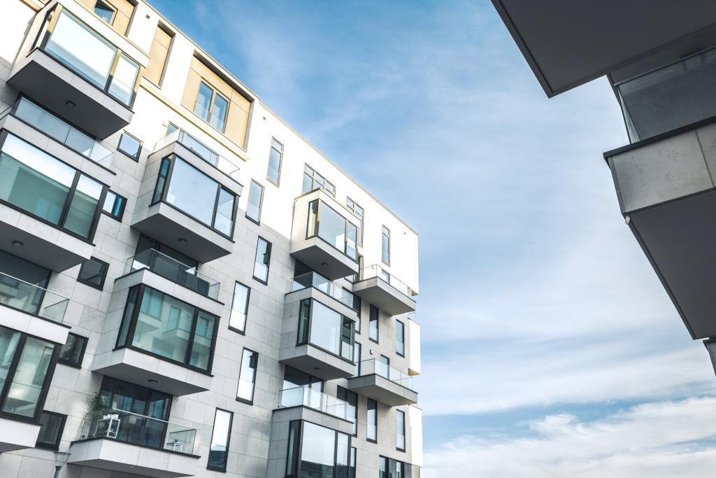 Moderne Wohnfassade mit Balkonen und großen Fenstern gegen den blauen Himmel.