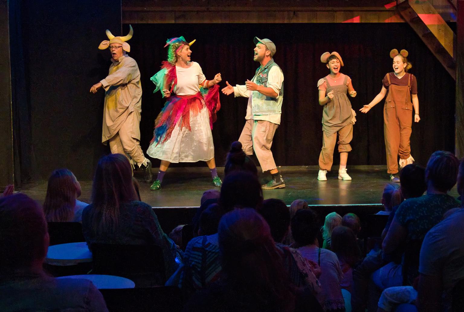 Menschen im Tierkostüm auf Bühne während einer Theateraufführung vor Publikum