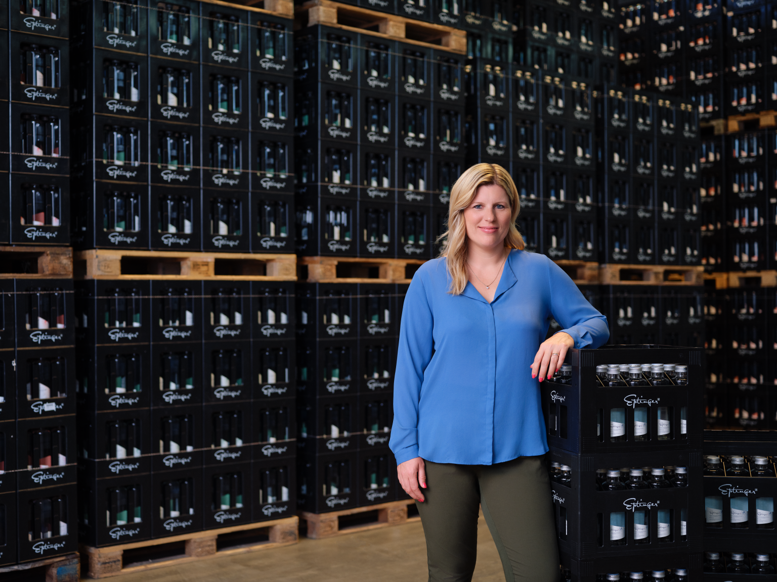 Frau in blauer Bluse steht vor Regalen mit schwarzen Bankboxen bei BLKB