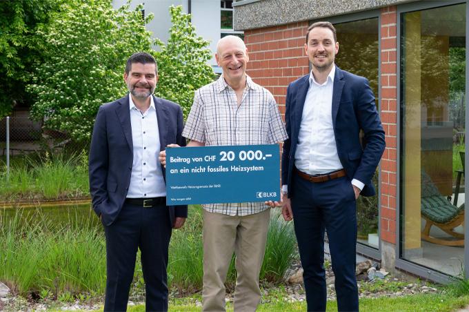 Mann mit Scheck über CHF 20 000 für ein umweltfreundliches Heizsystem.