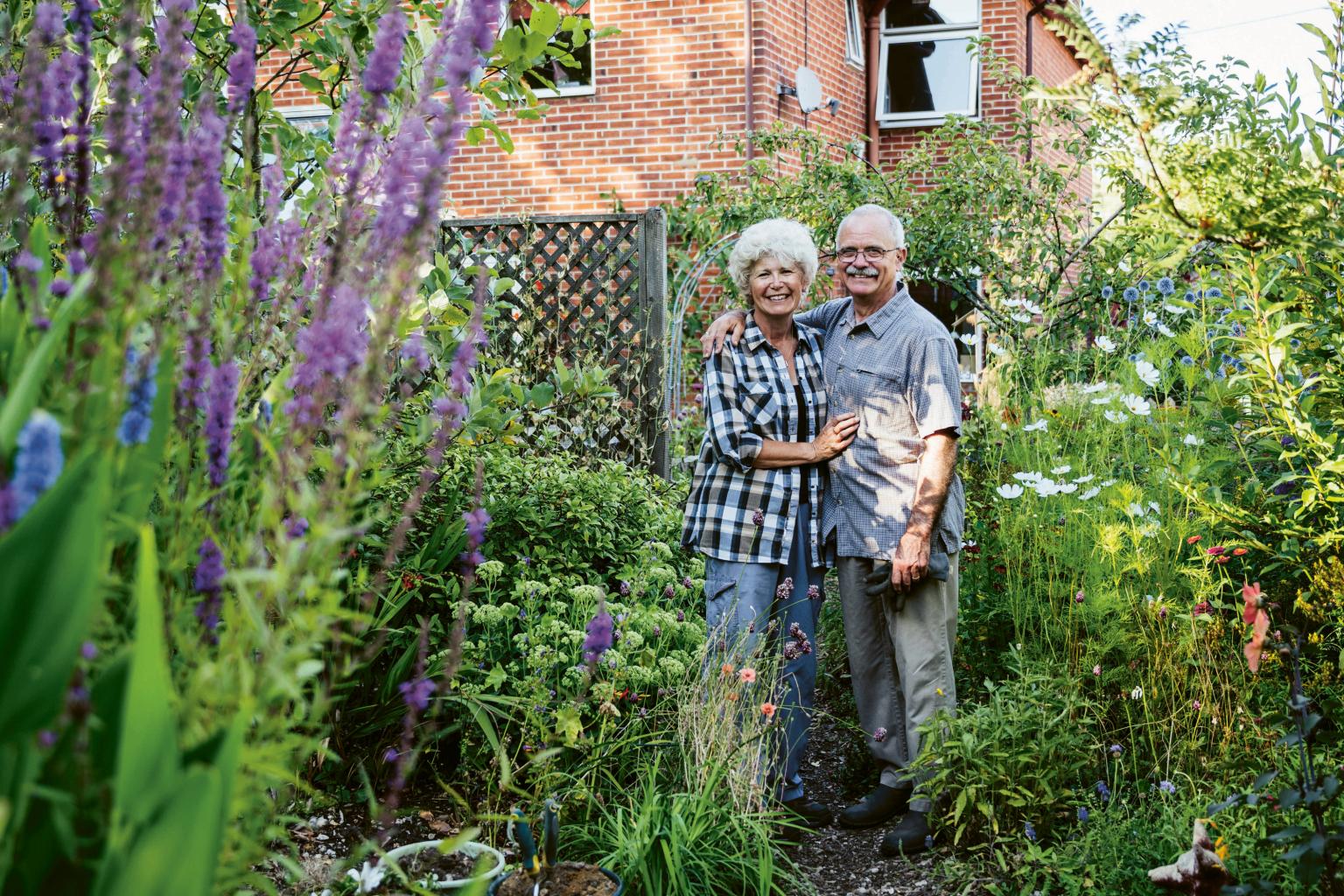 Ein älteres Paar lächelt im blühenden Garten und genießt die gemeinsame Zeit. aus dem Artikel Wohnen, Vererben, Sparen – finanzielle Klarheit im Alter