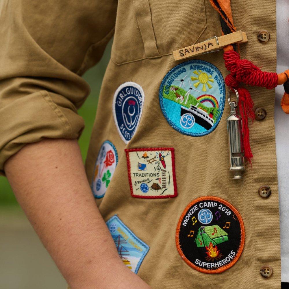 Fiona D’Elia trägt ein Scout-Shirt mit verschiedenen Pfadfinderabzeichen und einem orange-schwarzen Halstuch.