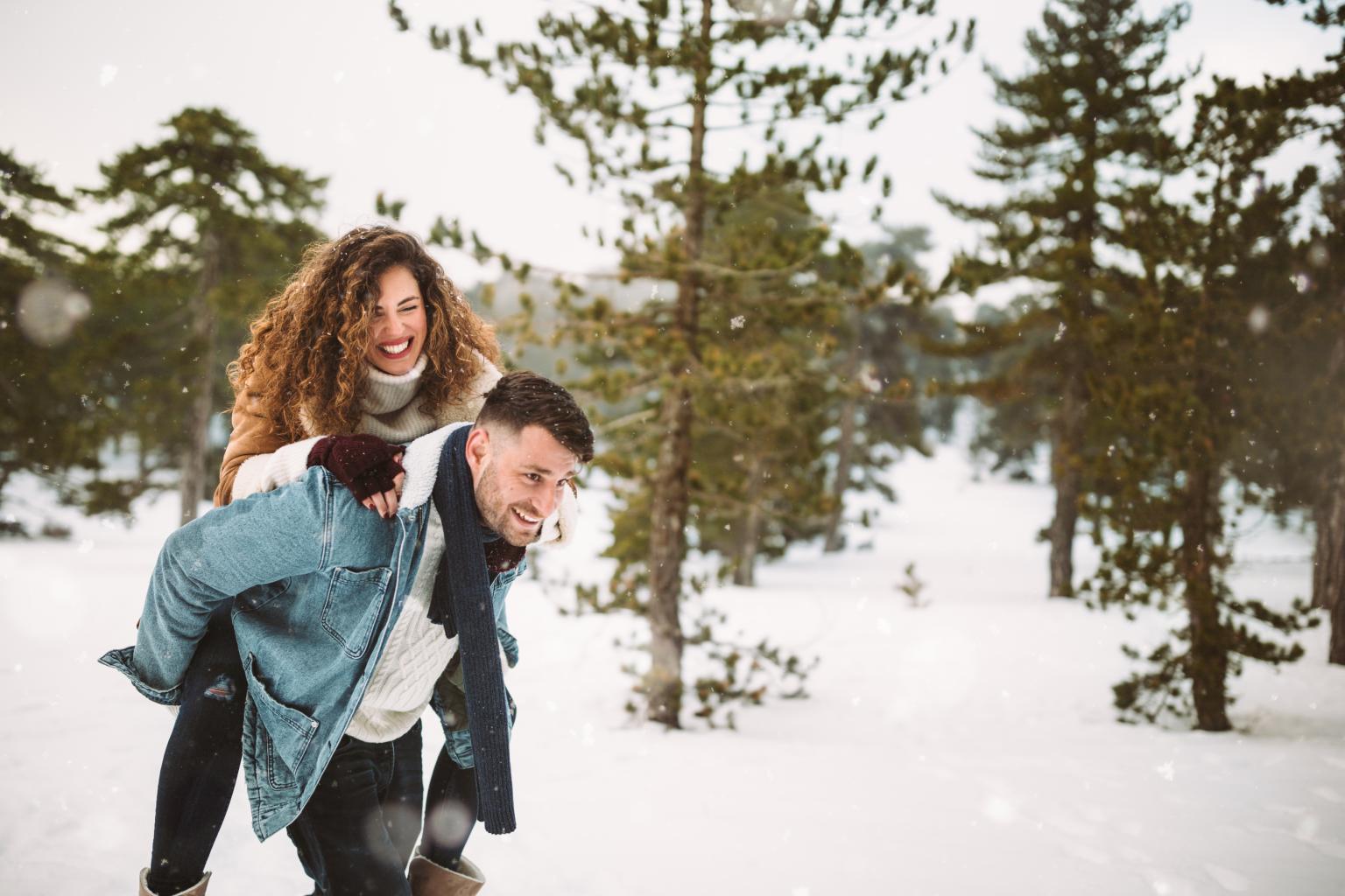 Paar beim Wandern in verschneiter Landschaft mit Baumgruppen im Hintergrund