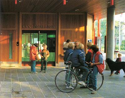 Eingang der Basellandschaftlichen Kantonalbank mit Besuchern und Fahrrad.