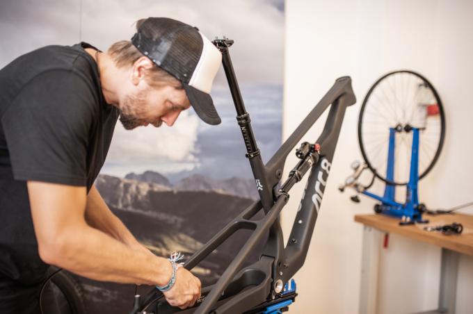 A young man from ARC8 Bicycles wearing a cap repairs a bicycle.