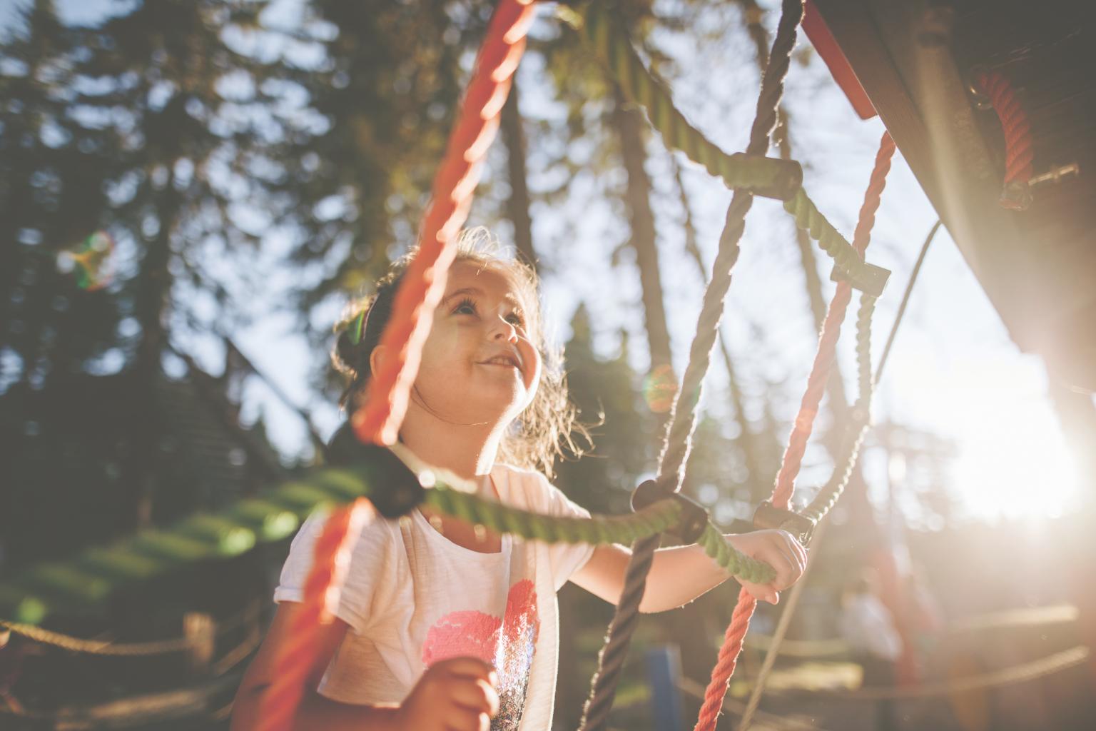 Kinder spielen auf Klettergerüst im Sonnenlicht in einem Park.