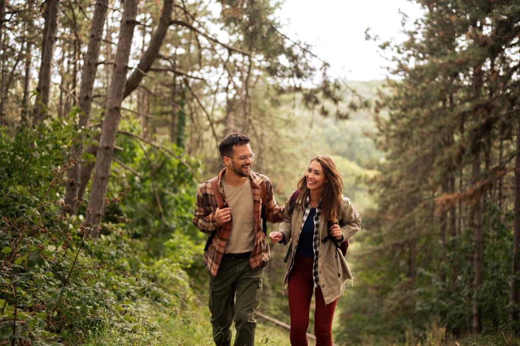 Ein junges Paar wandert fröhlich durch den Wald in der Natur.