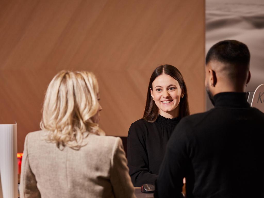 Zwei Kunden sprechen mit einer BLKB-Mitarbeiterin an der Theke. aus dem Artikel