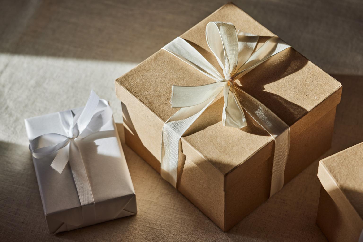 Braune und weisse Geschenkverpackungen in Papier und Schleifen, festlich präsentiert. aus dem Artikel Fairtrade-Gold und Green Gold als besonderes Weihnachtsgeschenk