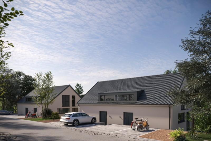 Moderne Einfamilienhäuser vor blauem Himmel mit Bäumen und Autos im Vordergrund am Baselweg in Hochwald.