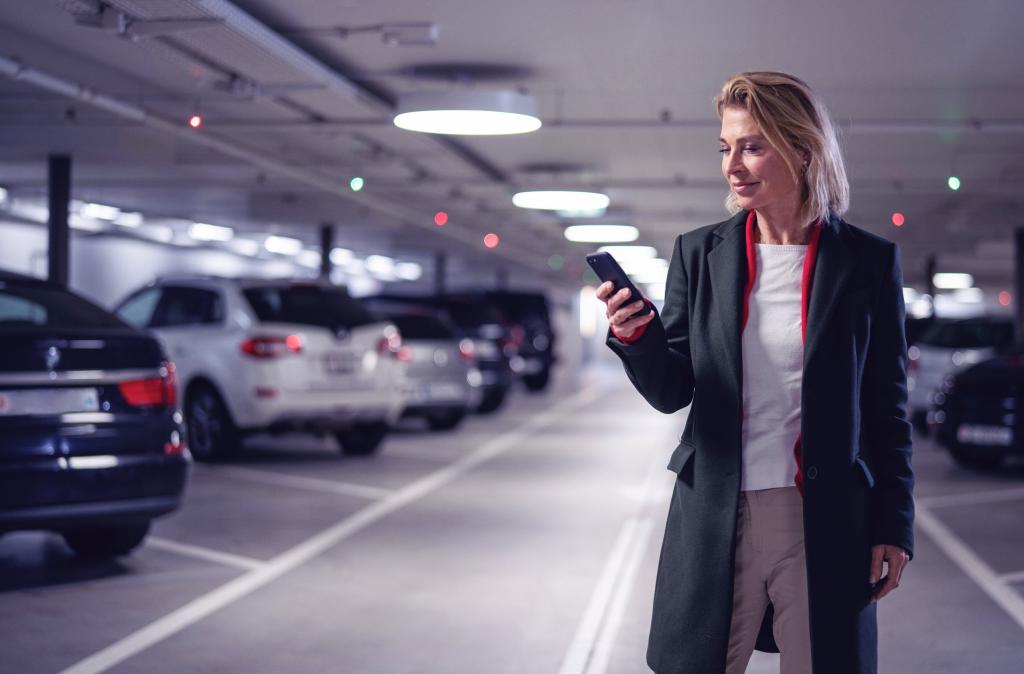 Eine Frau steht im Parkhaus und schaut auf ihr Smartphone.