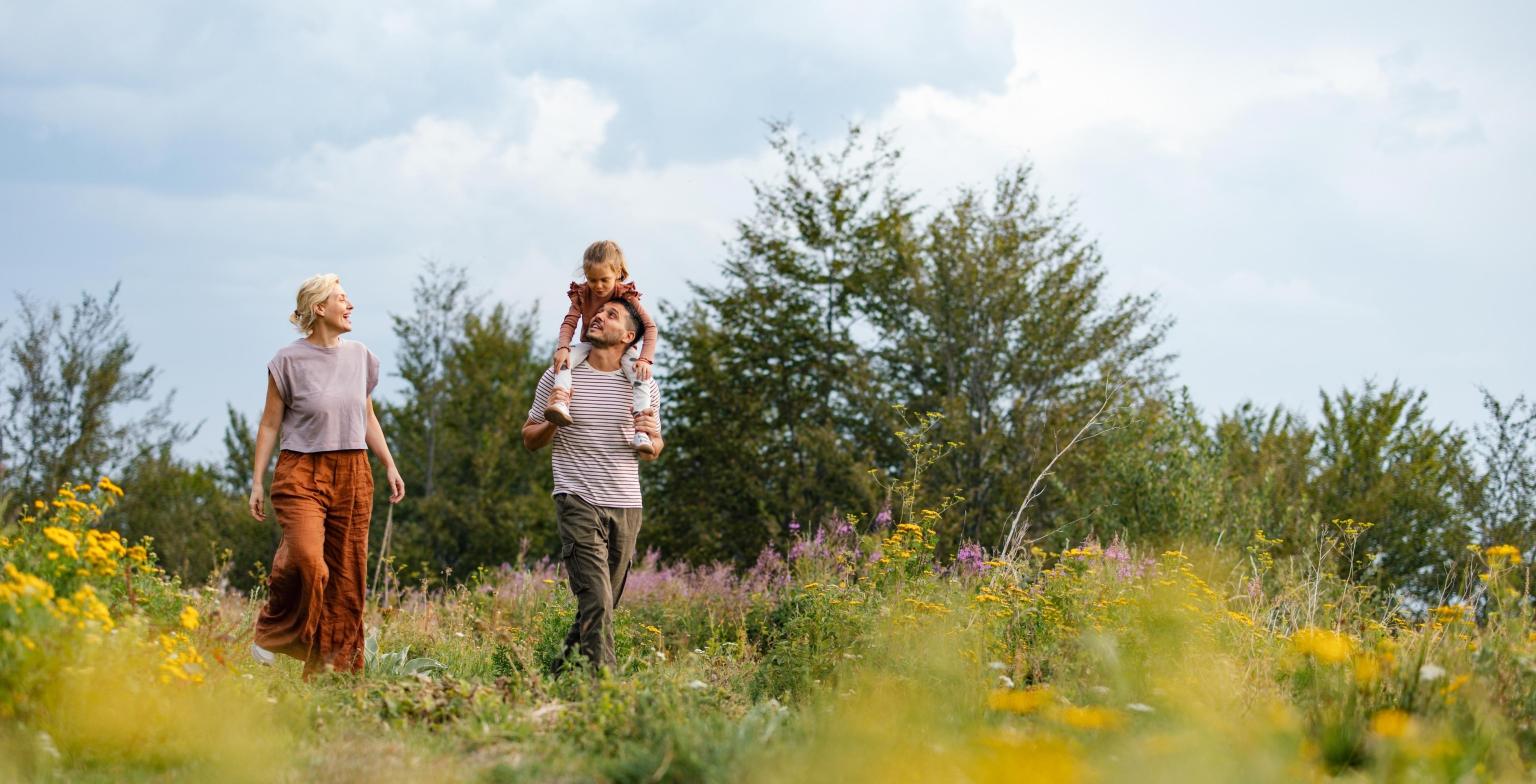 Eine junge Familie mit Kind im Grünen bei Sonnenschein in der Natur