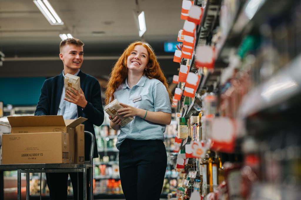 Zwei Menschen beim Einkaufen im Supermarkt, einen mit Getränke, die andere mit Geld.