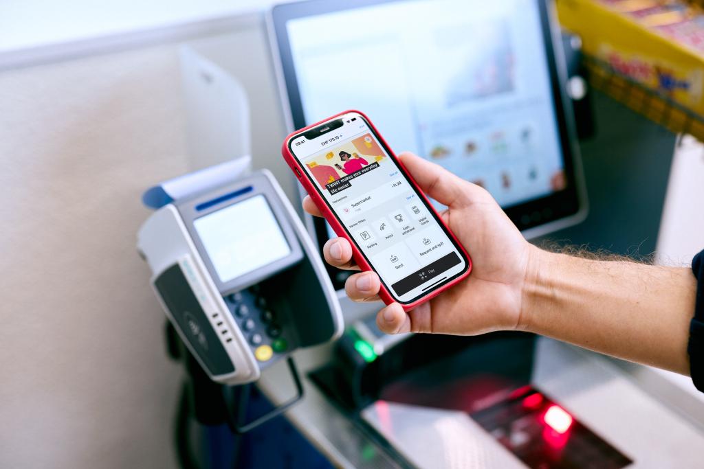 Person nutzt Smartphone an Zahlungsterminal bei der Basellandschaftlichen Kantonalbank