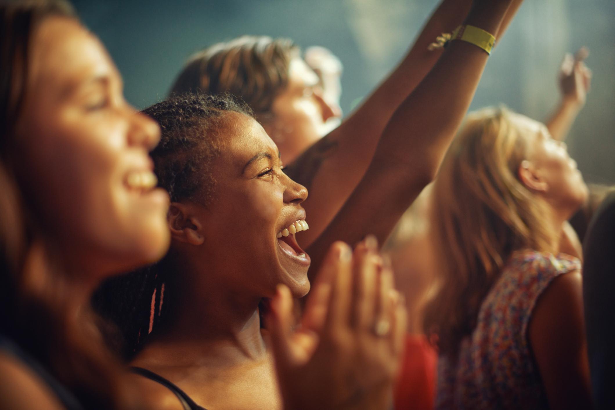 Junge Mädchen im Publikum genießen den Auftritt ihrer Lieblingsband in einem Konzert.