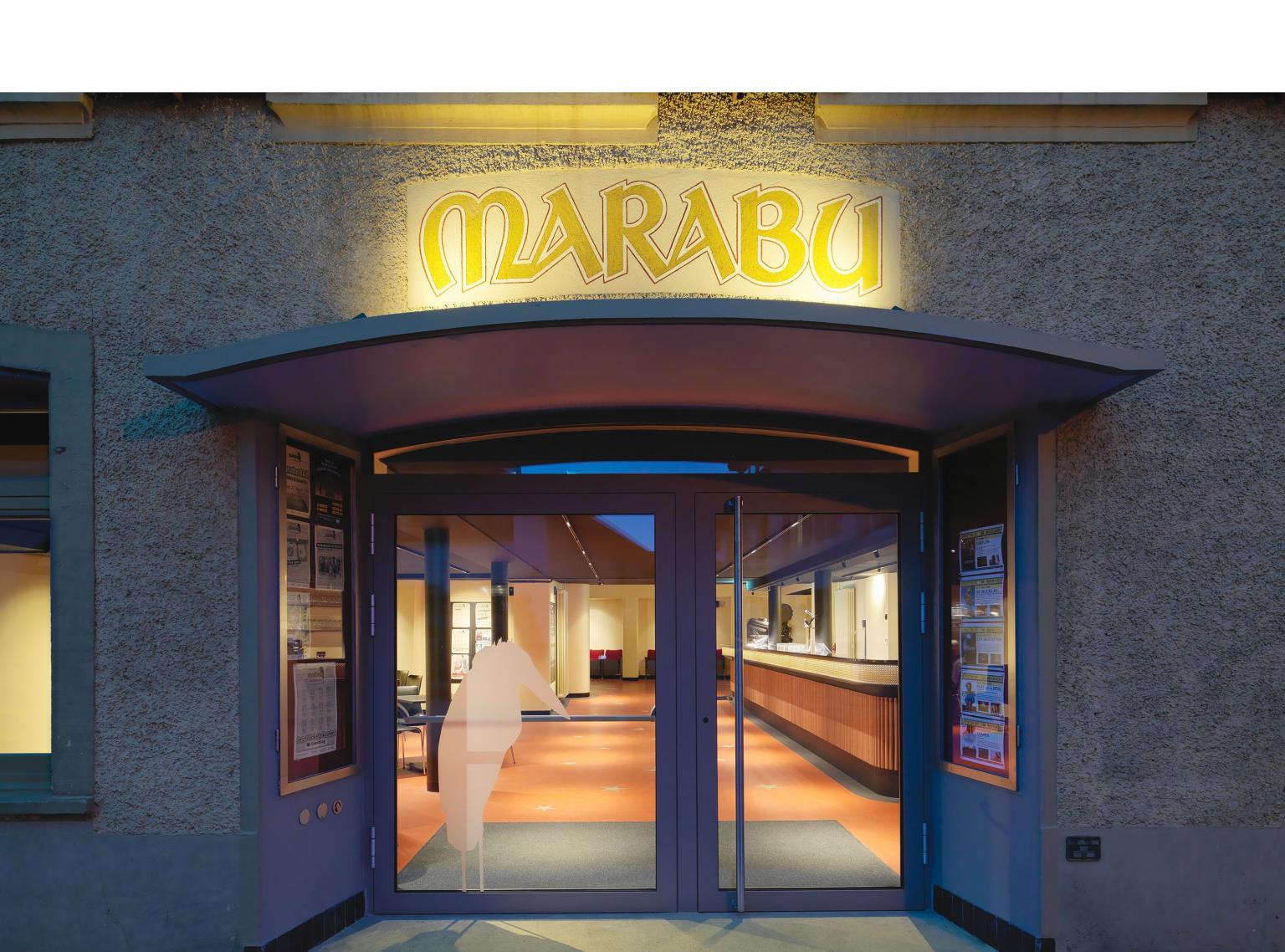 Eingang der Marabu Gelterkinden Theaterkasse mit beleuchtetem Marabu Schriftzug und Glasfronten.