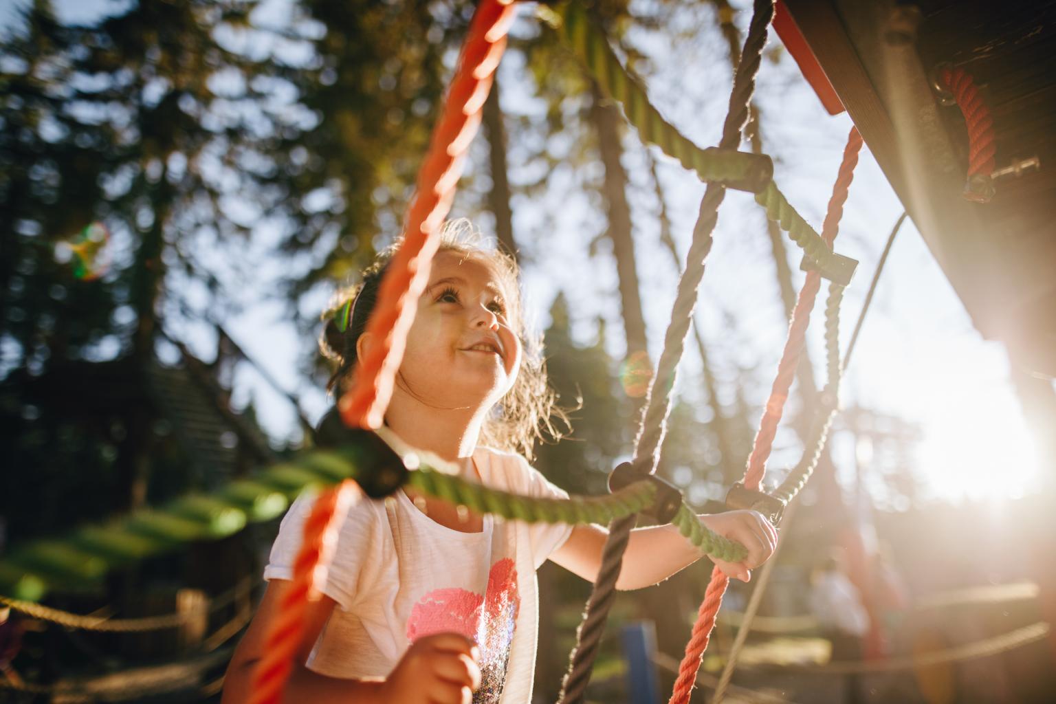 Kinder spielen auf Klettergerüst im Sonnenlicht in einem Park.