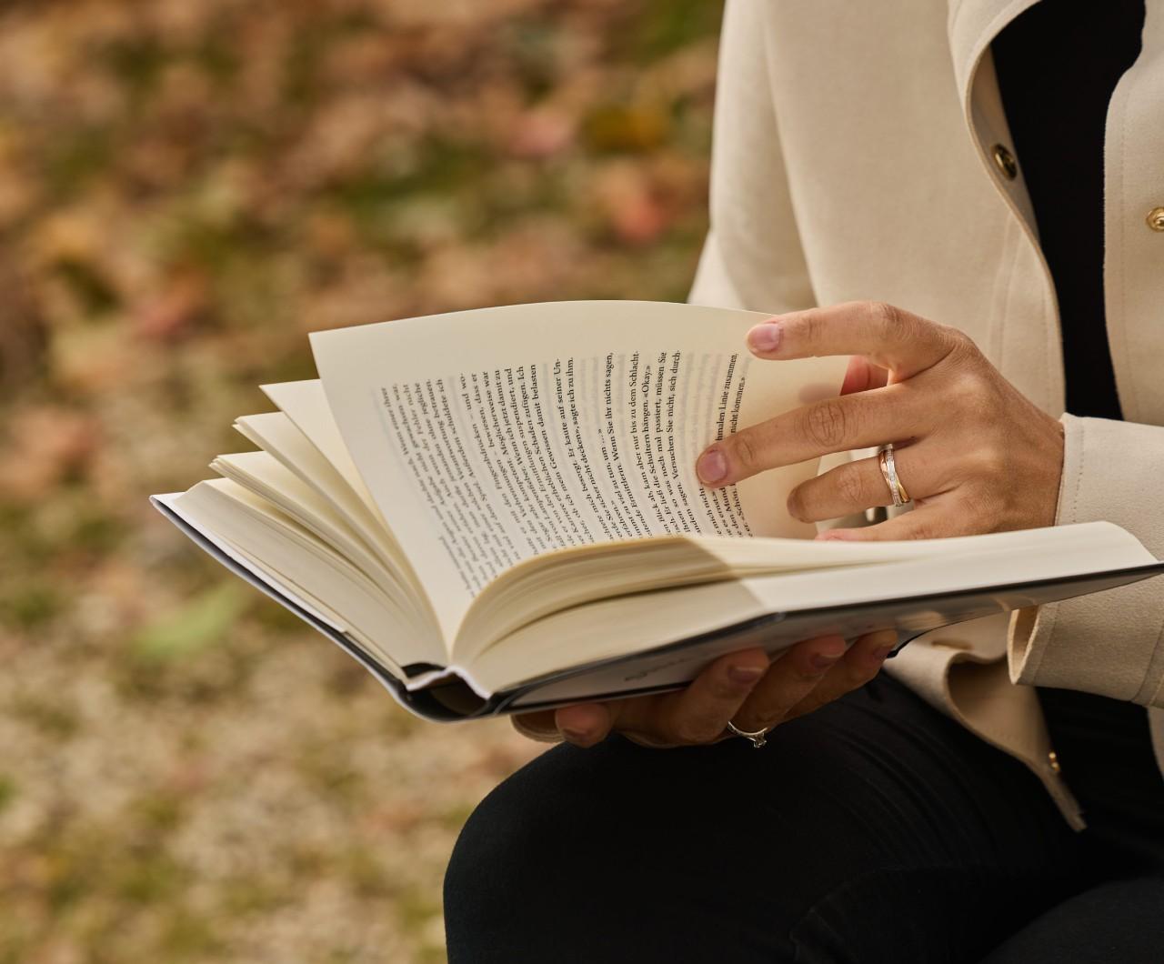 Betül Karabulut liest in einem Park ein Buch, entspannt und in ruhiger Umgebung.