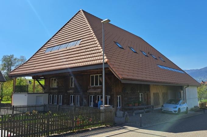 Ein modernes Haus in ländlicher Umgebung mit traditionellem Dach und Garten.