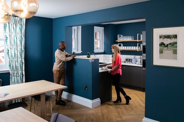 Two customers speaking and preparing their food in the communal kitchen