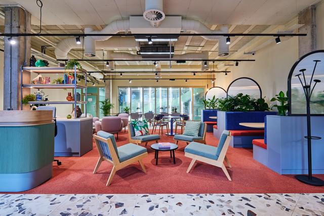 A reception area with four green chairs, plants are scattered around the area and a reception desk sits on the right hand side