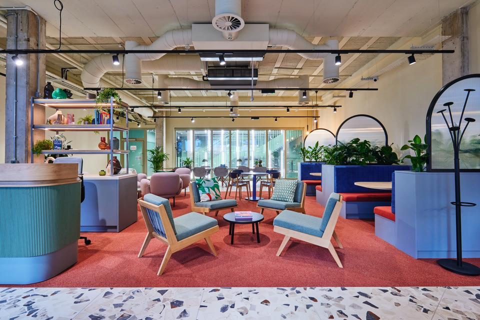 A reception area with four green chairs, plants are scattered around the area and a reception desk sits on the right hand side