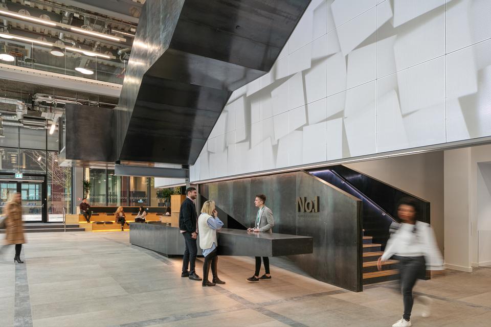 Two people speak to a receptionist at No.1 Circle Square while other workers walk to their offices