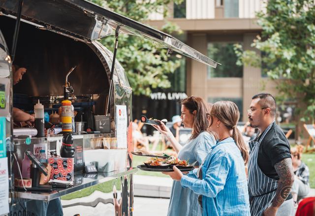 Three people queue at a food truck in Symphony Park