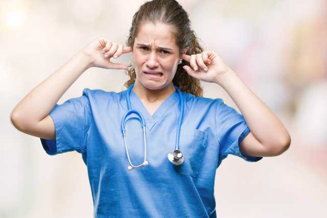 Enfermera tapándose los oídos por la alarma