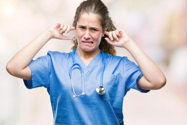 Infirmière se bouchant les oreilles à cause d'une alarme