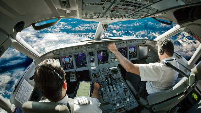 Imagen de la cabina de mando de un avión en la que los pilotos están manejando el cuadro de mandos.