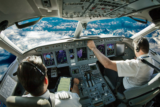 Foto della cabina di pilotaggio di un aereo, con i piloti che azionano i comandi del cockpit.