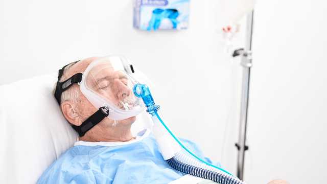 Взрослый пациент в маске для неинвазивной вентиляции (NIV) Pulmodyne