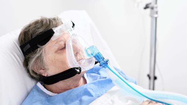 Patient in bed wearing full face mask