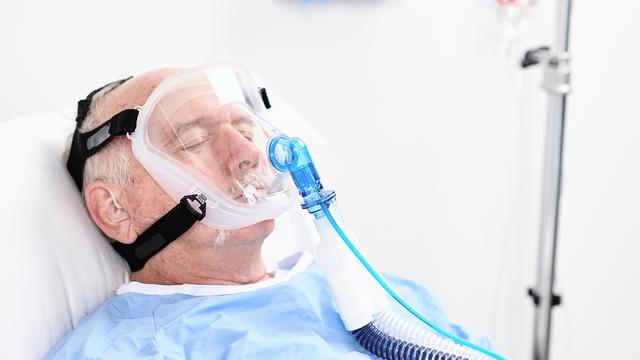 Patient mit Vollgesichtsmaske in einem Krankenbett