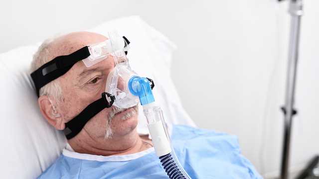 Patient alité portant un masque nasal