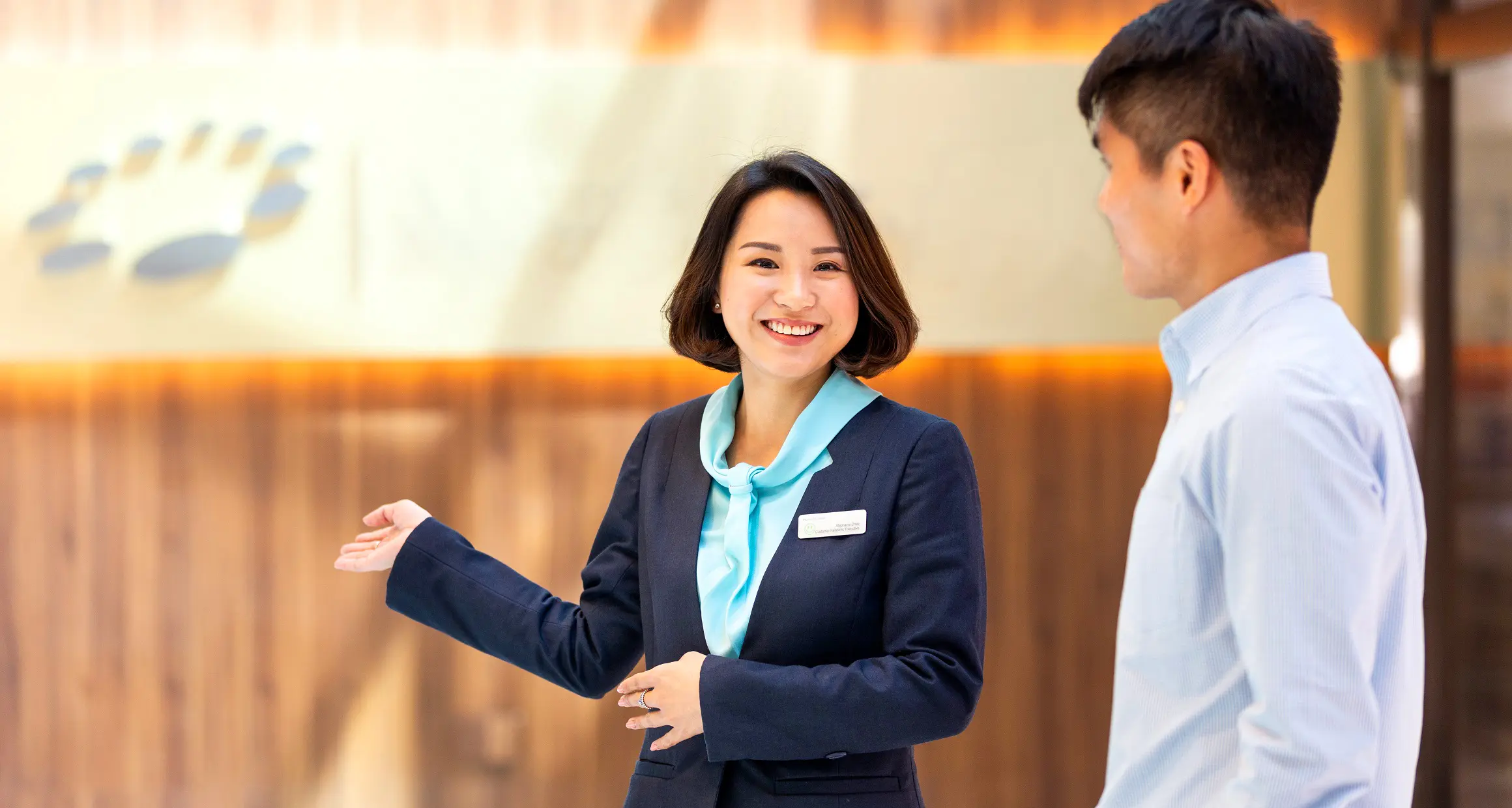 A kind looking front office lady smiling and welcoming visitors at the hospital entrance