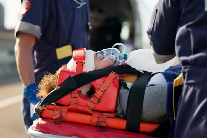 An injured patient being strapped to a stretcher before being transferred to a waiting ambulance
