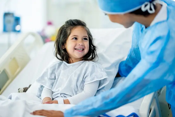 A 4 years old child patient in the hospital ward smiling at her doctor or nurse