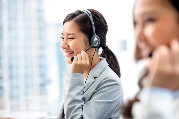2 smiling customer service representatives engaged in a call on their headsets